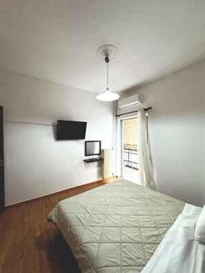 A bedroom with a bed, a television mounted on the wall, and a window with curtains. - An Athenian gem by the Acropolis (Athens)