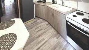 A kitchen with light wood cabinets, a white countertop, a stove, and a refrigerator. - An Athenian gem by the Acropolis (Athens)