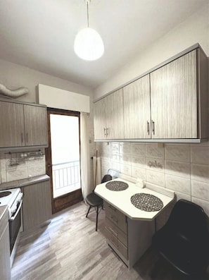 A compact kitchen with a stove, a sink, and a dining area with a chair. - An Athenian gem by the Acropolis (Athens)