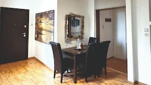 A spacious room with a wooden floor, a dining table with chairs, a wall-mounted mirror, and recessed ceiling lights. - An Athenian gem by the Acropolis (Athens)