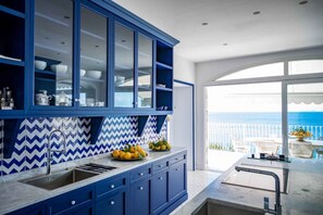 Eine moderne Küche mit blauen Schränken und Blick auf das Meer.