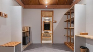 A narrow hallway with a wooden bench on the left, a sink with a wooden frame in the center, and shelves on the right. - D'Lagoon Dive Resort (Pulau Lembeh)