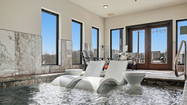 Ett spaområde med ett bubbelbad, solstolar och utsikt över omgivningarna.