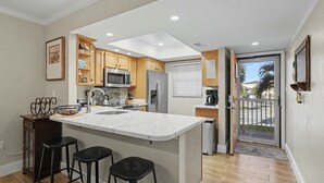Een moderne keuken met een centraal eiland, houten kastjes en roestvrijstalen apparatuur, met uitzicht naar buiten.