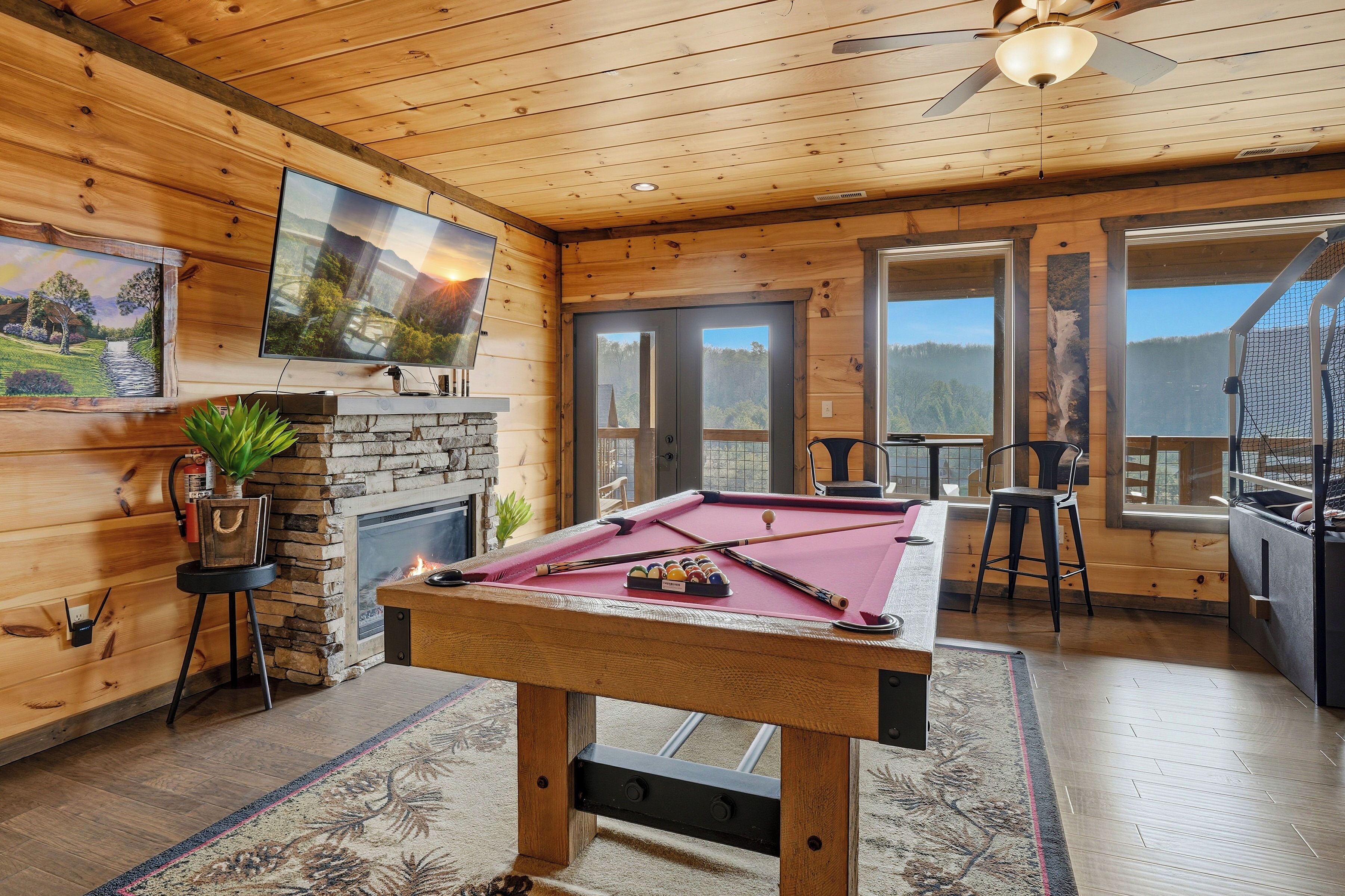 Une pièce chaleureuse avec une table de billard, une cheminée et un grand téléviseur fixé au mur.