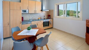 Een moderne keuken met houten kastjes, een ingebouwde magnetron en een groot raam met uitzicht op het groen.