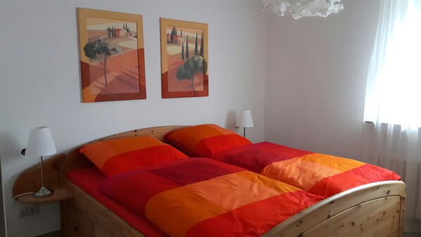A bed with a wooden frame, two wall-mounted lamps, and two landscape paintings.