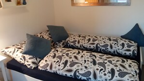 Une chambre à coucher avec un lit, des oreillers, un miroir et un mur orné d’un cadre de tableau.
