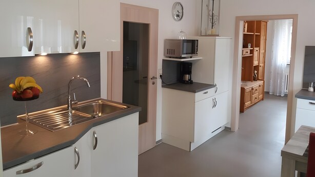 Une cuisine moderne équipée d’un évier, de placards, d’un four à micro-ondes et d’une horloge murale.