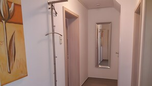 Un couloir avec un porte-manteau, une porte et un miroir.