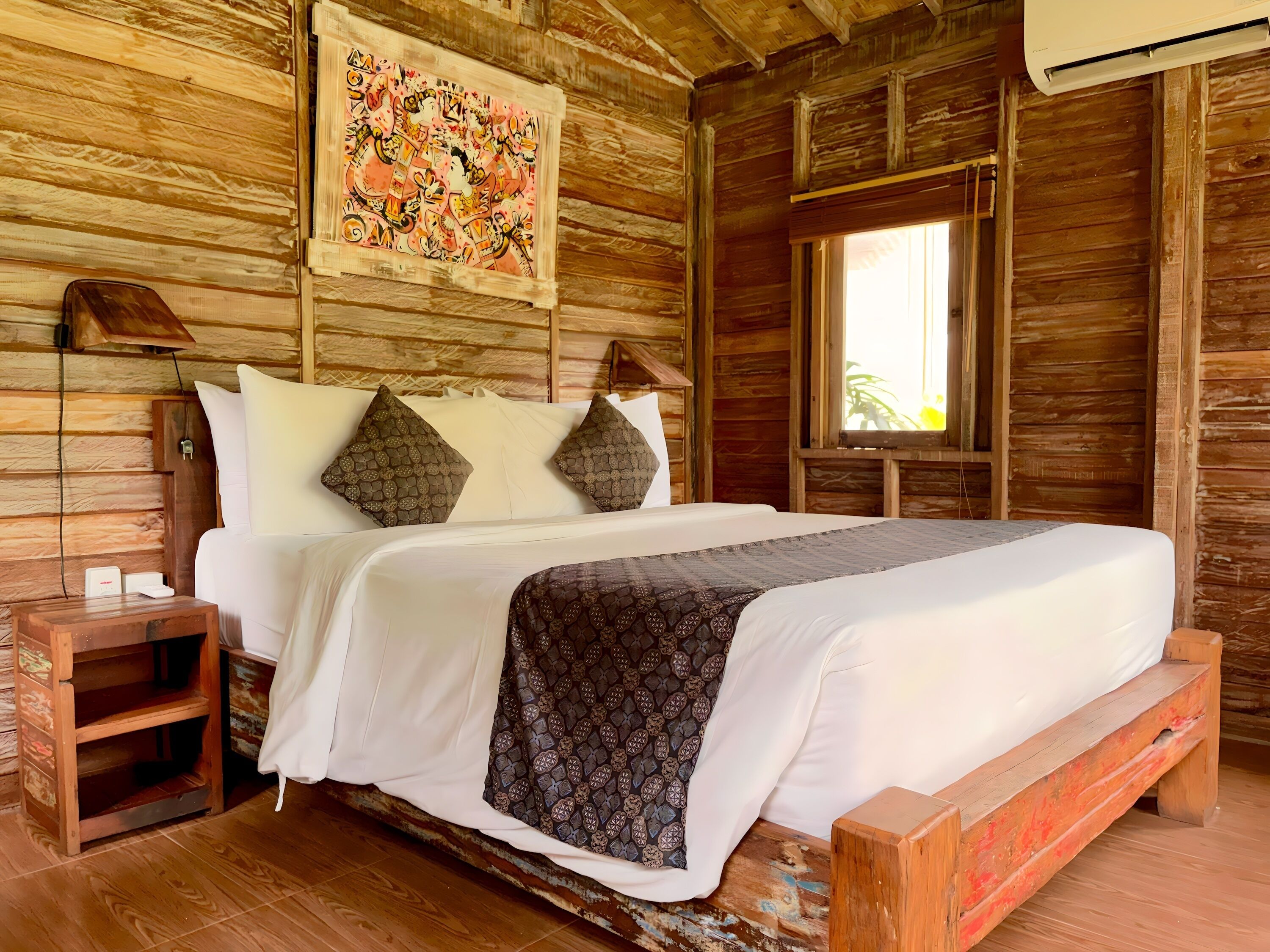 Una habitación de madera con una cama, una mesita de noche, un cuadro en la pared y una ventana.