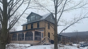 A two-story house with a large glass windowed porch and a steeply pitched roof. - Beautifully restored Farmhouse on 64 acres+++ (Kimberley)