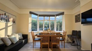 Un coin repas avec une table et des chaises, un canapé et un téléviseur fixé au mur.