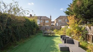 Un jardin avec une pelouse verdoyante, une table et des chaises, et une clôture en bois.