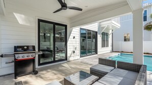 A covered outdoor area with a grill, seating, and a pool. - Sunny Cove - Private Pool Oasis - Beautiful Patio (Santa Rosa Beach)