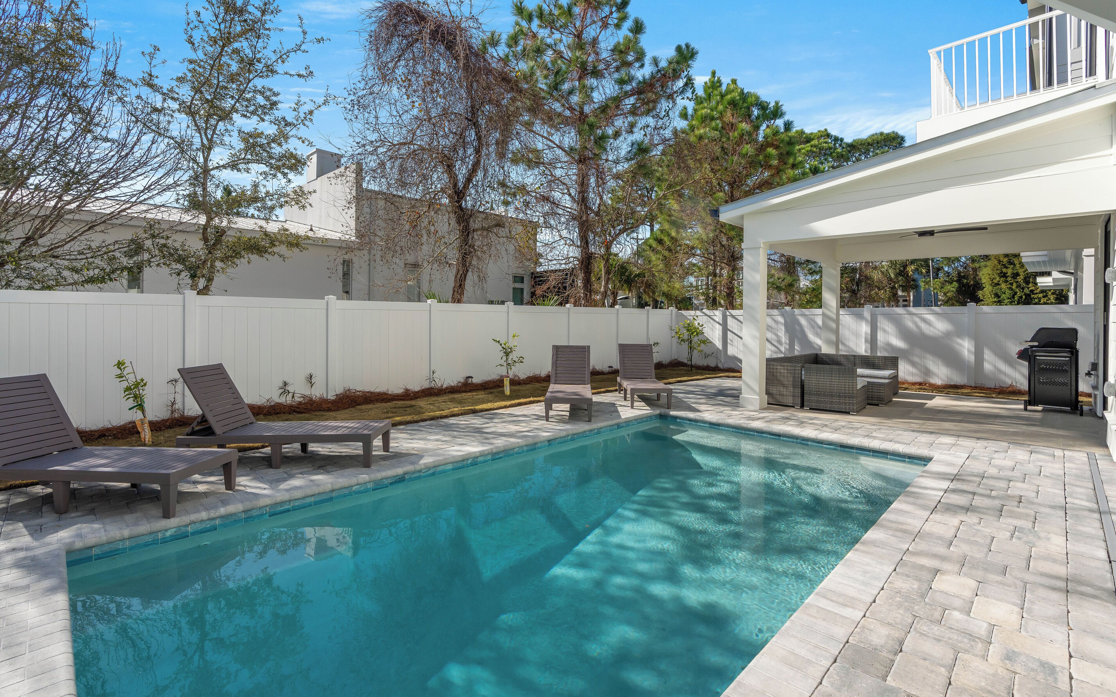 Une piscine avec des chaises longues et un patio couvert.