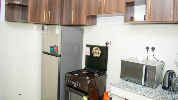 Eine Küche mit Holzausstattung, einem Gasherd, einem Kühlschrank, einer Mikrowelle und einer Kaffeemaschine.