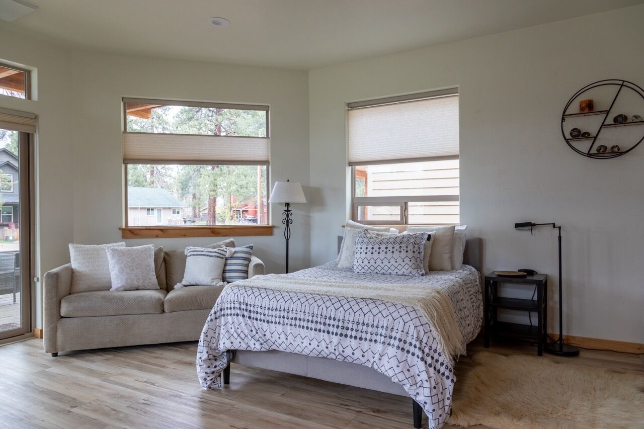 Un dormitorio con cama, sofá, lámpara y estante fijado a la pared.