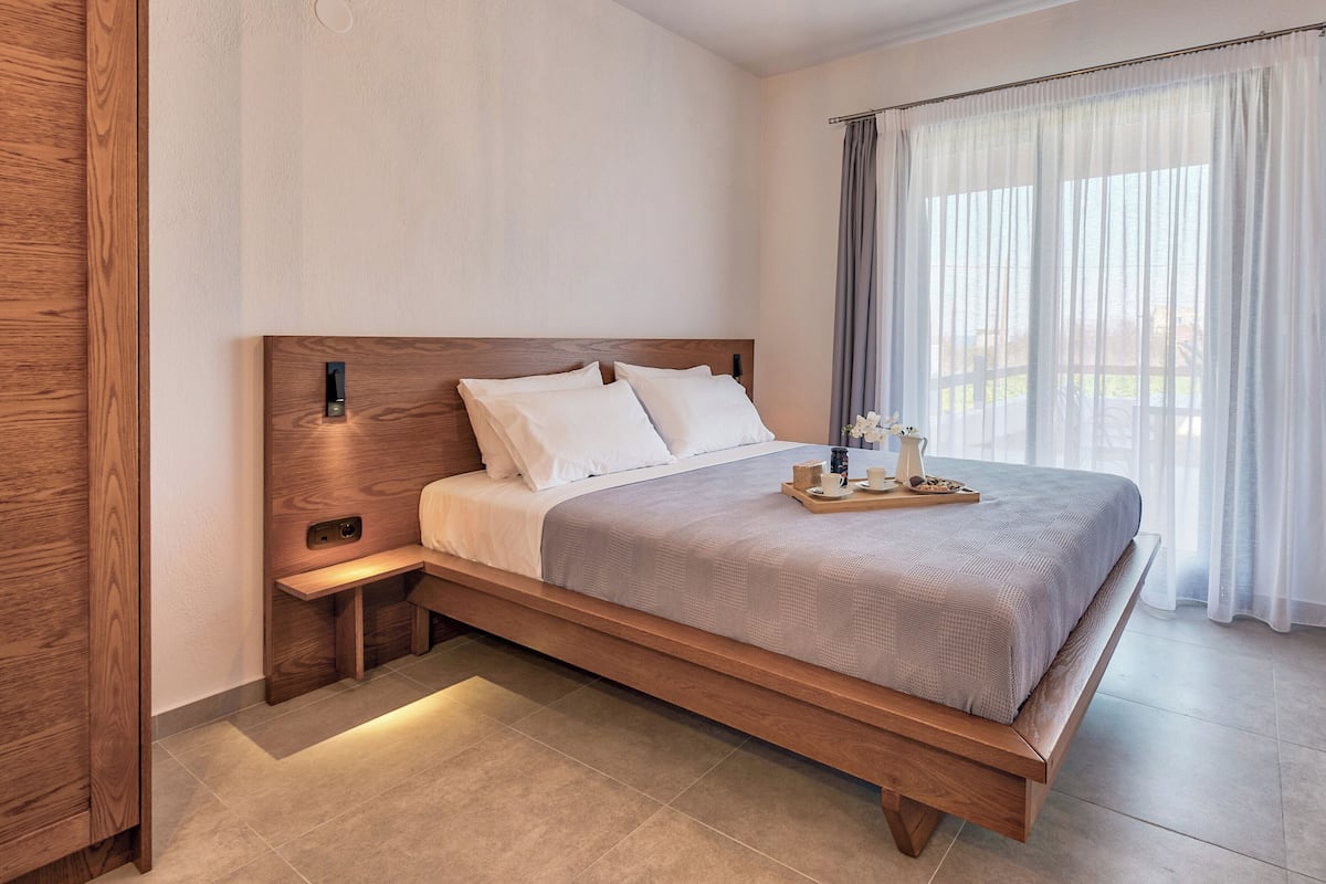 Ein modernes Schlafzimmer mit einem Holzbettrahmen, weißer Bettwäsche und einem Nachttisch mit Lampe.