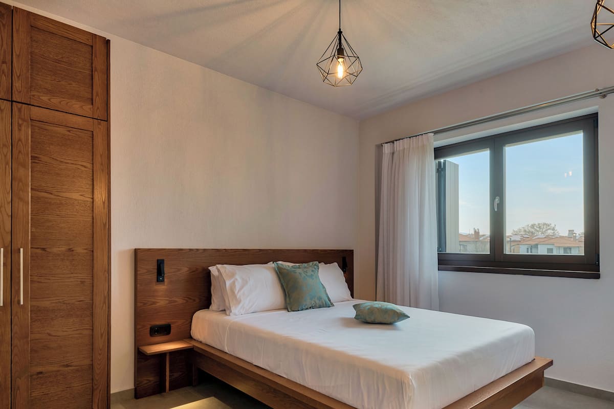 Ein Schlafzimmer mit einem hölzernen Bett, einem Nachttisch, einem Kleiderschrank und einem Fenster mit Blick.