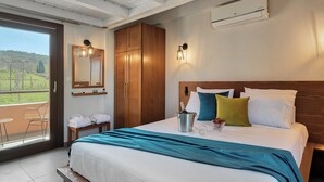 Een hotelkamer met een groot bed, een houten garderobe en een balkon met uitzicht op het platteland.