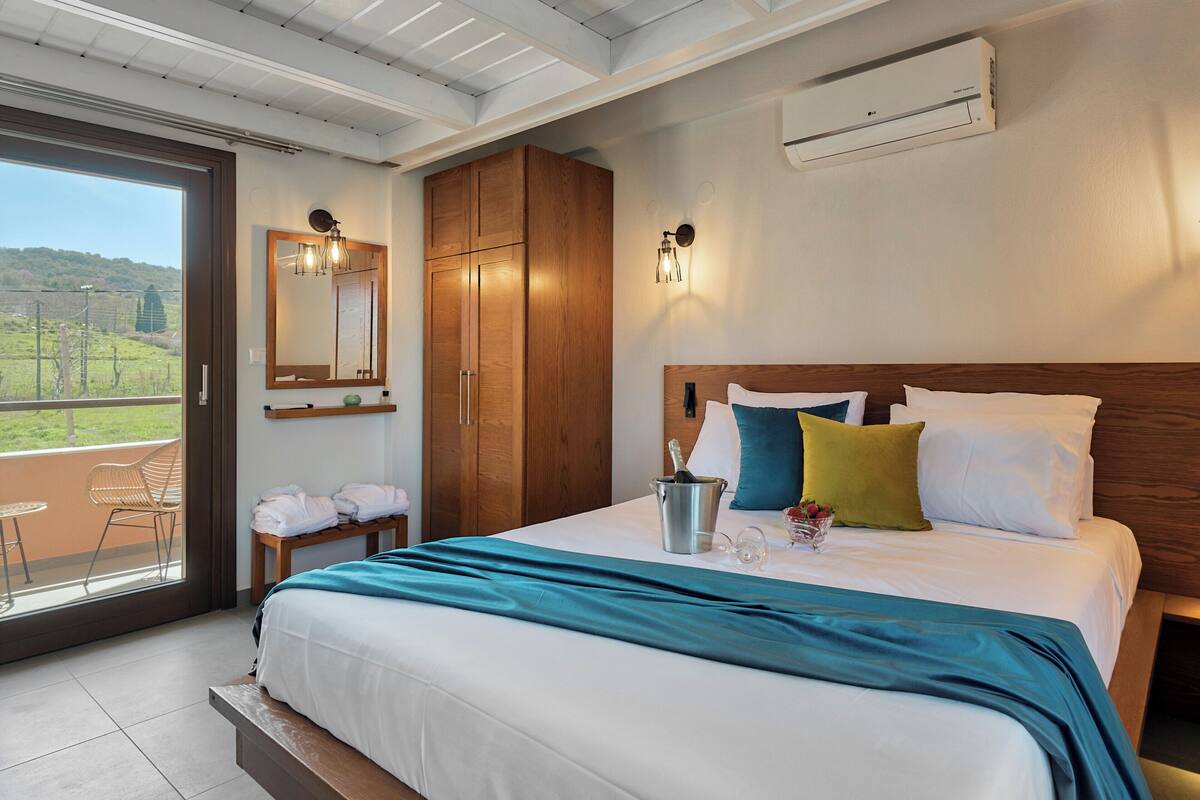 Ein Hotelzimmer mit einem großen Bett, einem Holzschrank und einem Balkon mit Blick auf die Landschaft.