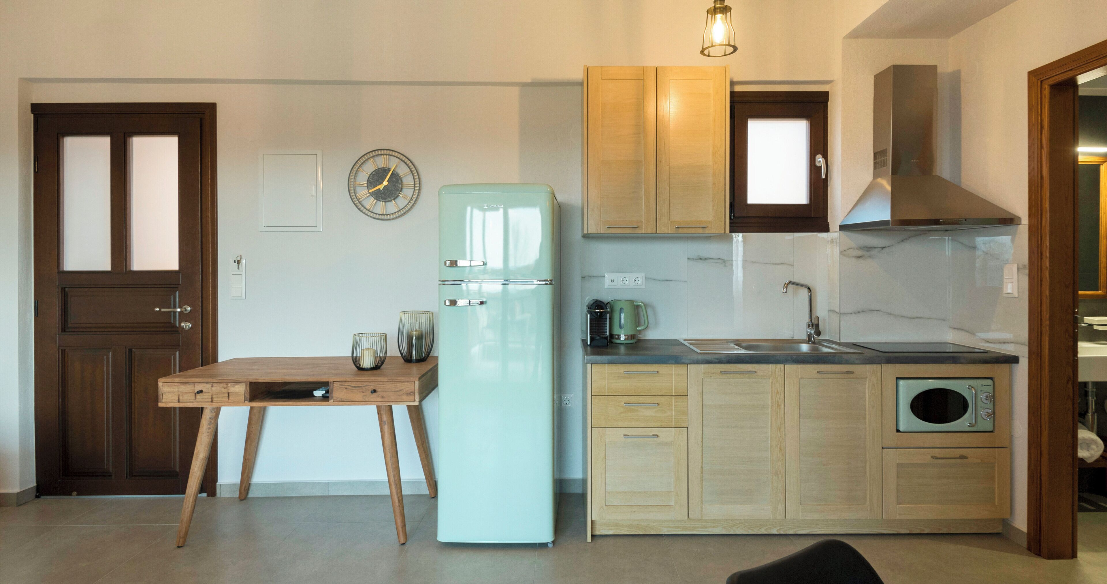 Una cocina compacta con un refrigerador antiguo, armarios de madera, un lavamanos y un microondas.