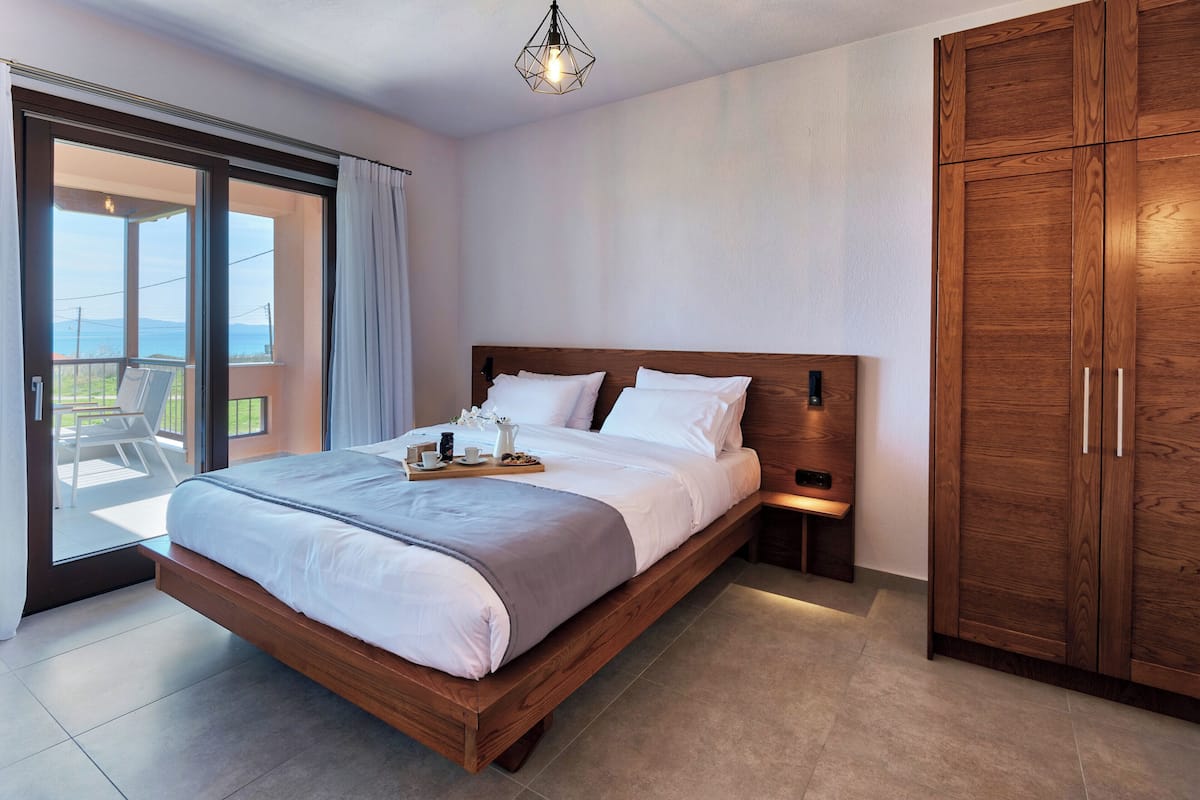 Ein Schlafzimmer mit einem hölzernen Bett, einem Nachttisch, einem Kleiderschrank und einem Balkon mit Blick.
