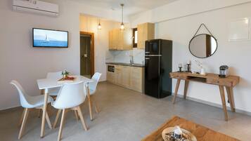 Una cocina moderna con un refrigerador negro, armarios de madera y un comedor con sillas blancas y una mesa de madera.
