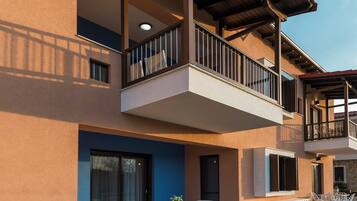 A multi-story building with a balcony, outdoor seating area, and a well-maintained lawn.