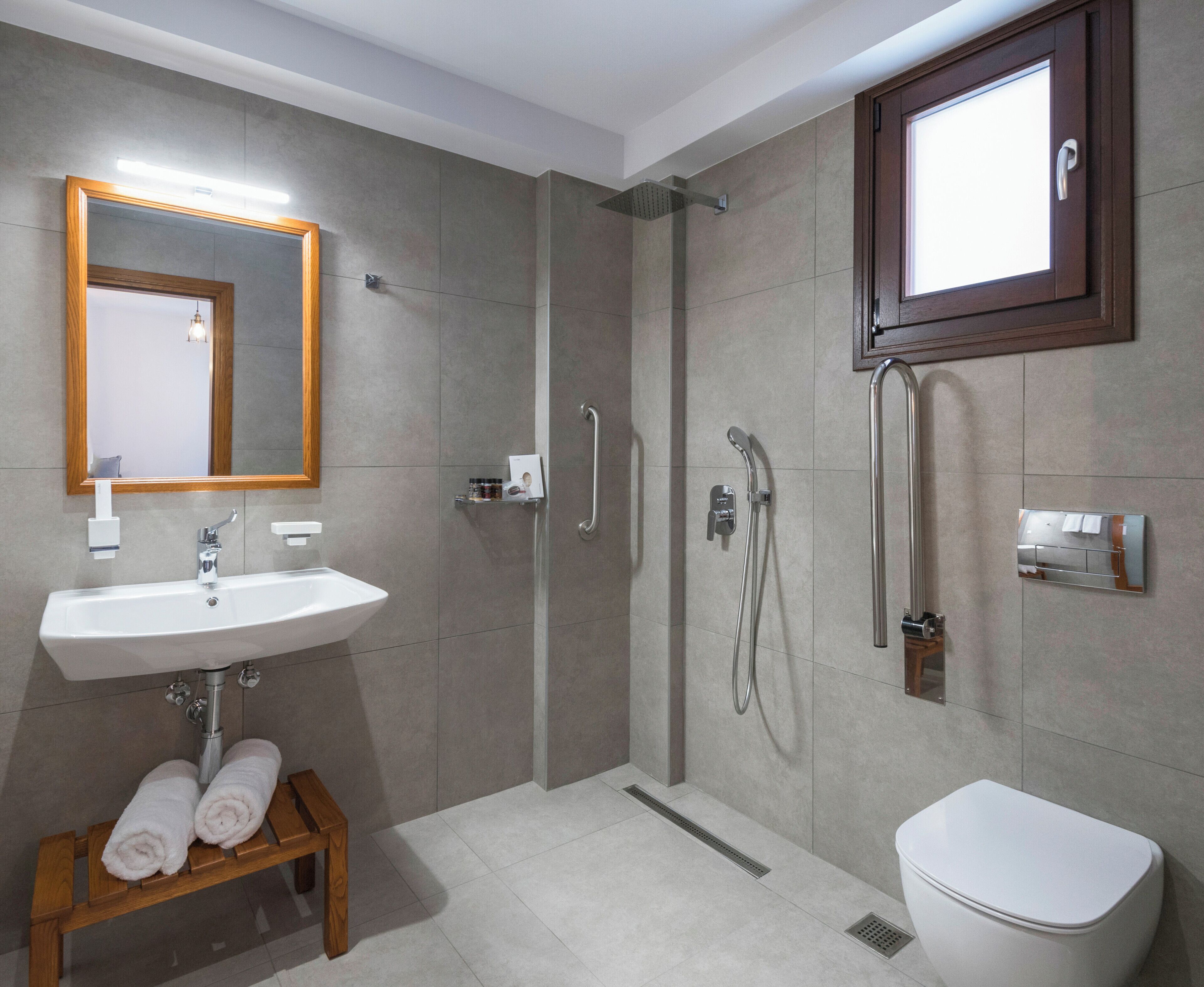 Un baño moderno con lavabo, espejo, ducha e inodoro.