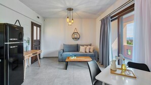 Een moderne woonkamer met een grijze bank, een houten salontafel en een zwarte koelkast.