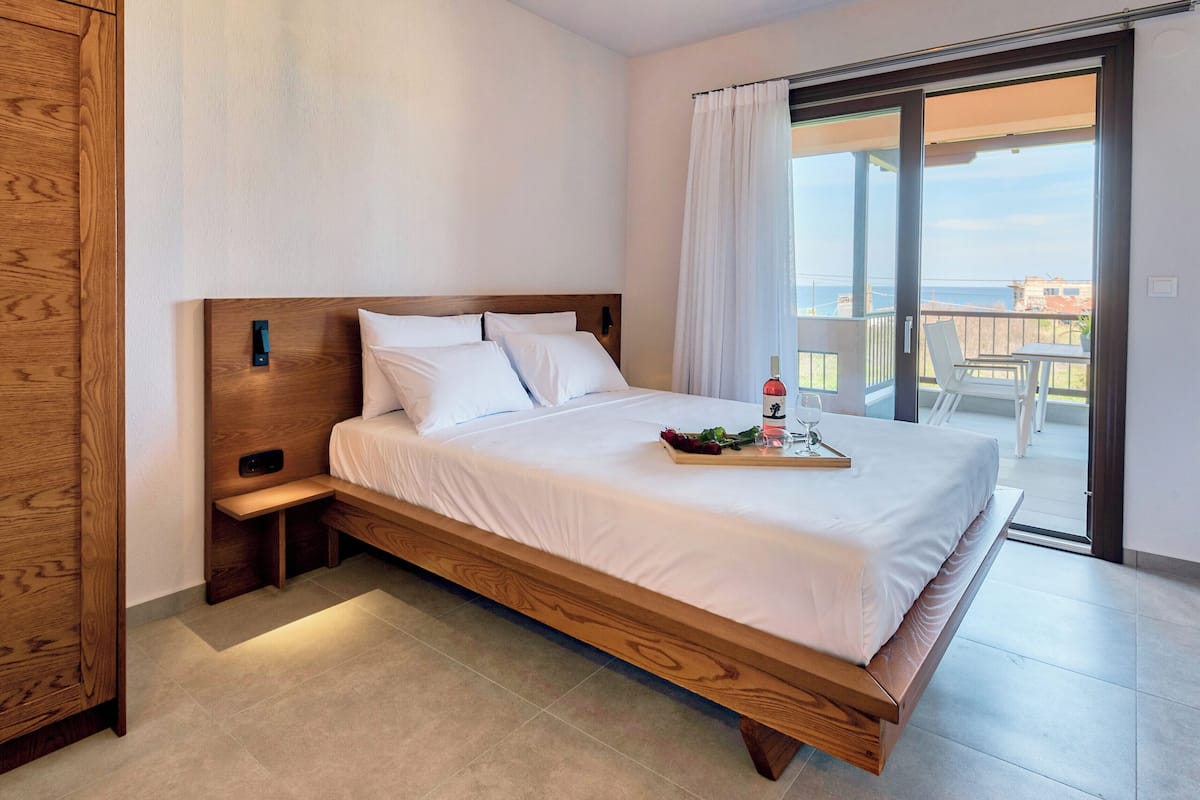 Ein Schlafzimmer mit einem Holzbett, einem Nachttisch, einem Schrank aus Holz und einem Balkon mit Blick.