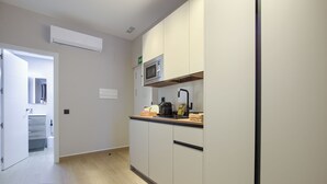 Una cocina moderna con armarios blancos, un microondas y una cafetera sobre la encimera.