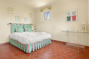 Un dormitorio con una cama, una mesita de noche, un ventanal y una pared decorada con cuadros.