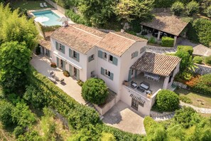 Una casa de dos plantas con piscina, zona de estar exterior y jardín.