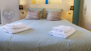 A neatly made bed with pillows, a folded towel, and a bedside lamp. - Apt le NID - Sea view in the village (Tourrettes-sur-Loup)