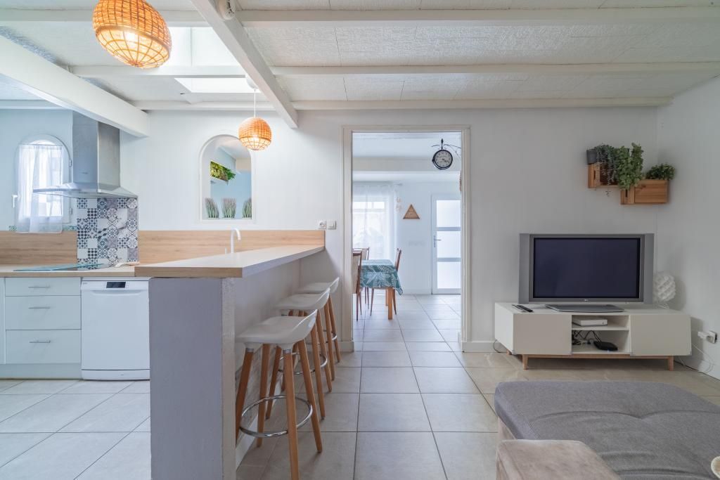 Et moderne køkken med en bar, et spiseområde og en opholdsstue med tv.