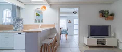 A modern kitchen with a bar area, a dining space, and a living area with a television.