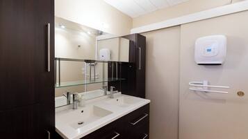 Een moderne badkamer met twee wasbakken, een grote spiegel en een handdoekdispenser.