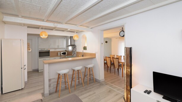 Une cuisine moderne dotée d’un îlot central, de tabourets de bar et d’un coin repas avec des chaises en bois.