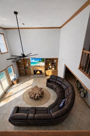 A spacious living room with a curved sectional sofa, a fireplace, and a television. - New Listing! Custom Waterfront Home! Heated Pool, Boat Dock, Game Room (Navarre)