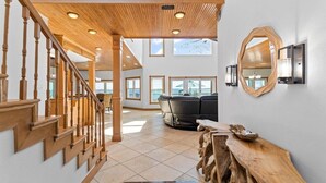 Un vaste espace de vie agrémenté d’un escalier en bois, d’un canapé en cuir noir et d’une table basse en bois.