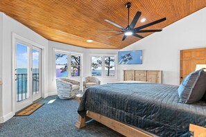 A bedroom with a large bed, a ceiling fan, and a view of the ocean through large windows. - New Listing! Custom Waterfront Home! Heated Pool, Boat Dock, Game Room (Navarre)