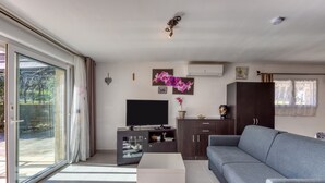 Una sala de estar moderna con un sofá, televisor, mueble y puerta corrediza de vidrio.