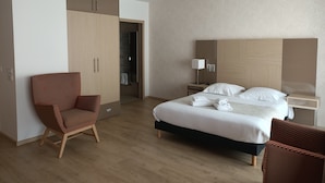 Une chambre d’hôtel avec un lit, une chaise, une armoire, une table de chevet et une lampe.