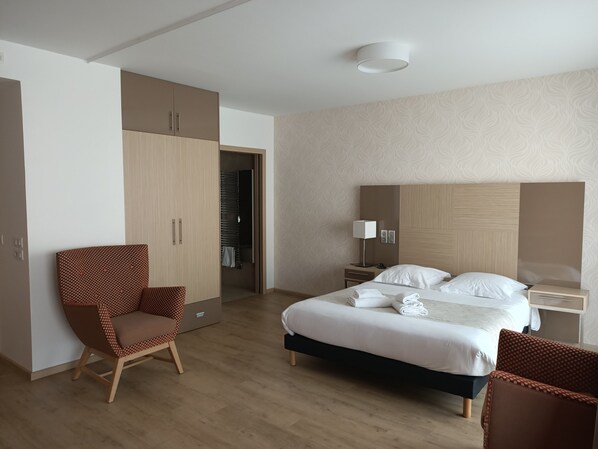 A hotel room with a bed, a chair, a wardrobe, a nightstand, and a lamp. - Appart One Chambéry (Chambéry)