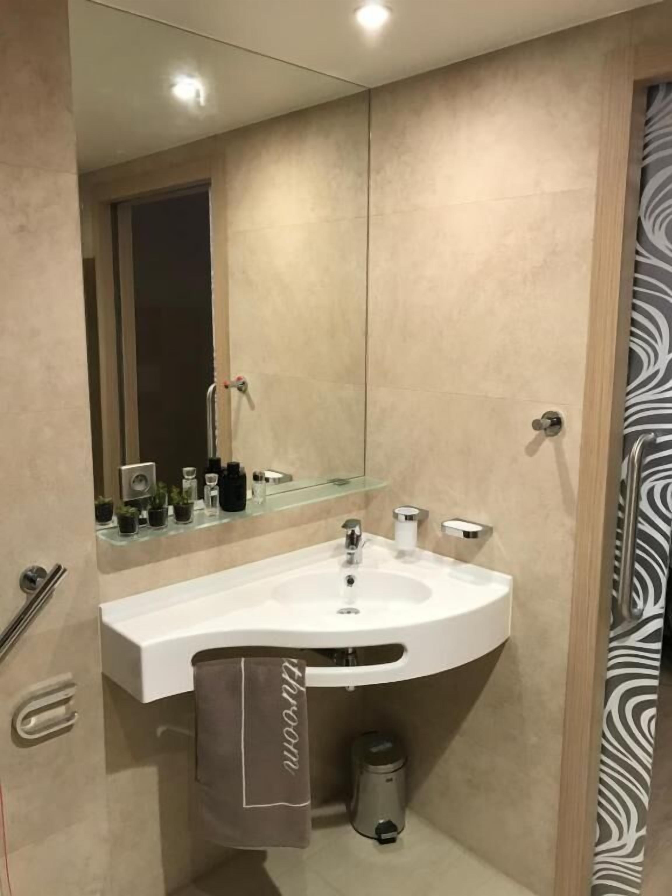 Ein modernes Badezimmer mit Waschbecken, Spiegel und Handtuchhalter.