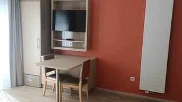 Een moderne kamer met een houten bureau, een flatscreen-tv, een bed met een beddegoed met een zebraprint en een rode accentmuur.