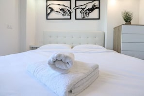A neatly made bed with a folded towel in the foreground, a tufted headboard, and two framed artworks on the wall. - Well-connected to downtown, the Port of Civitavecchia, and Fiumicino Airport (La Massimina-Casal Lumbroso)